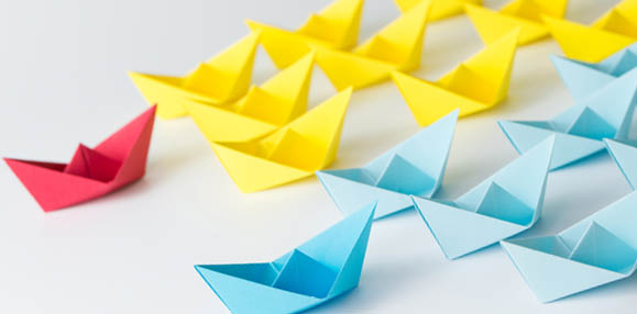Business competition concept using two different color origami paper boats