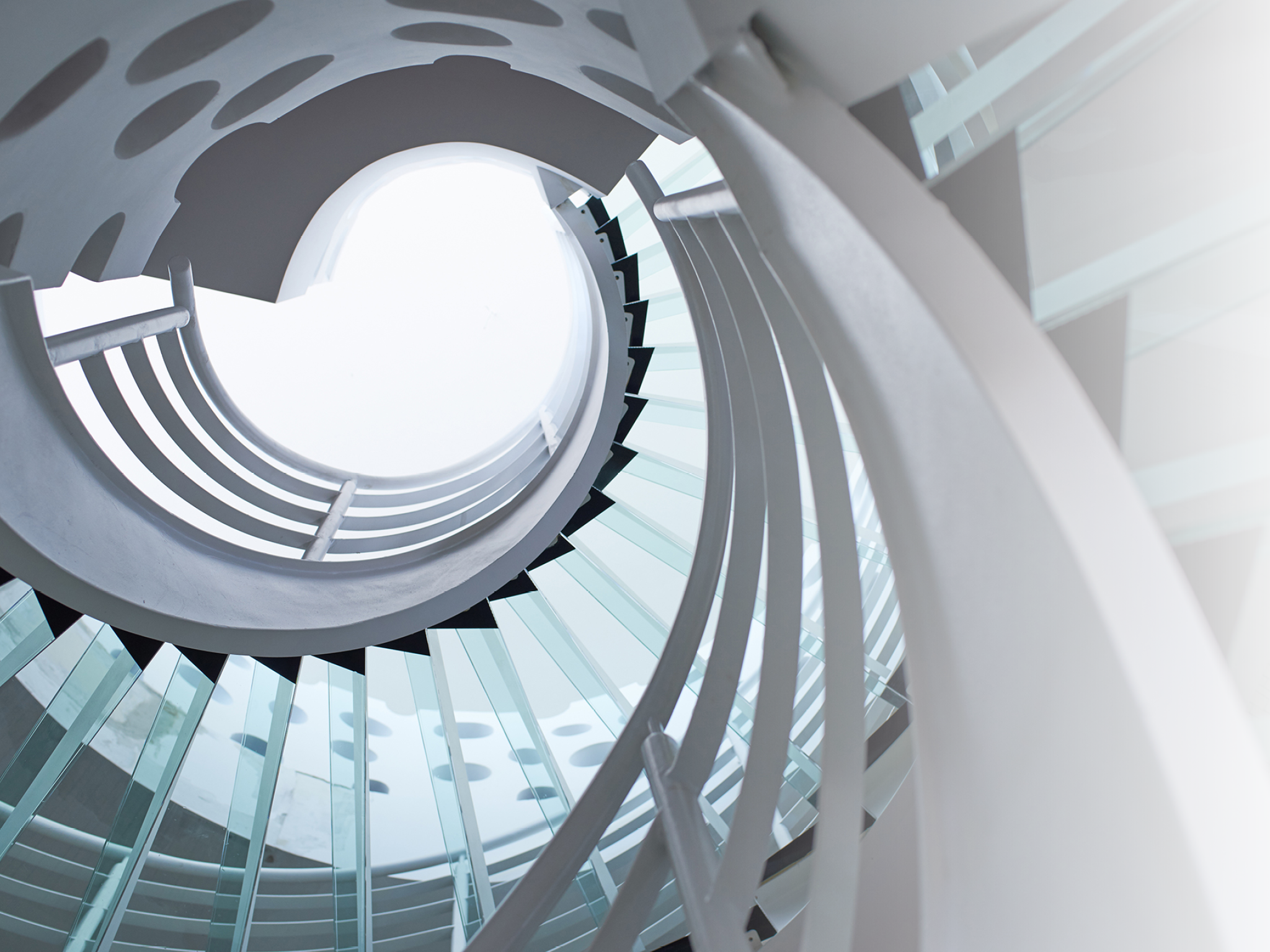modern glass spiral staircase with metallic hand-rails.
