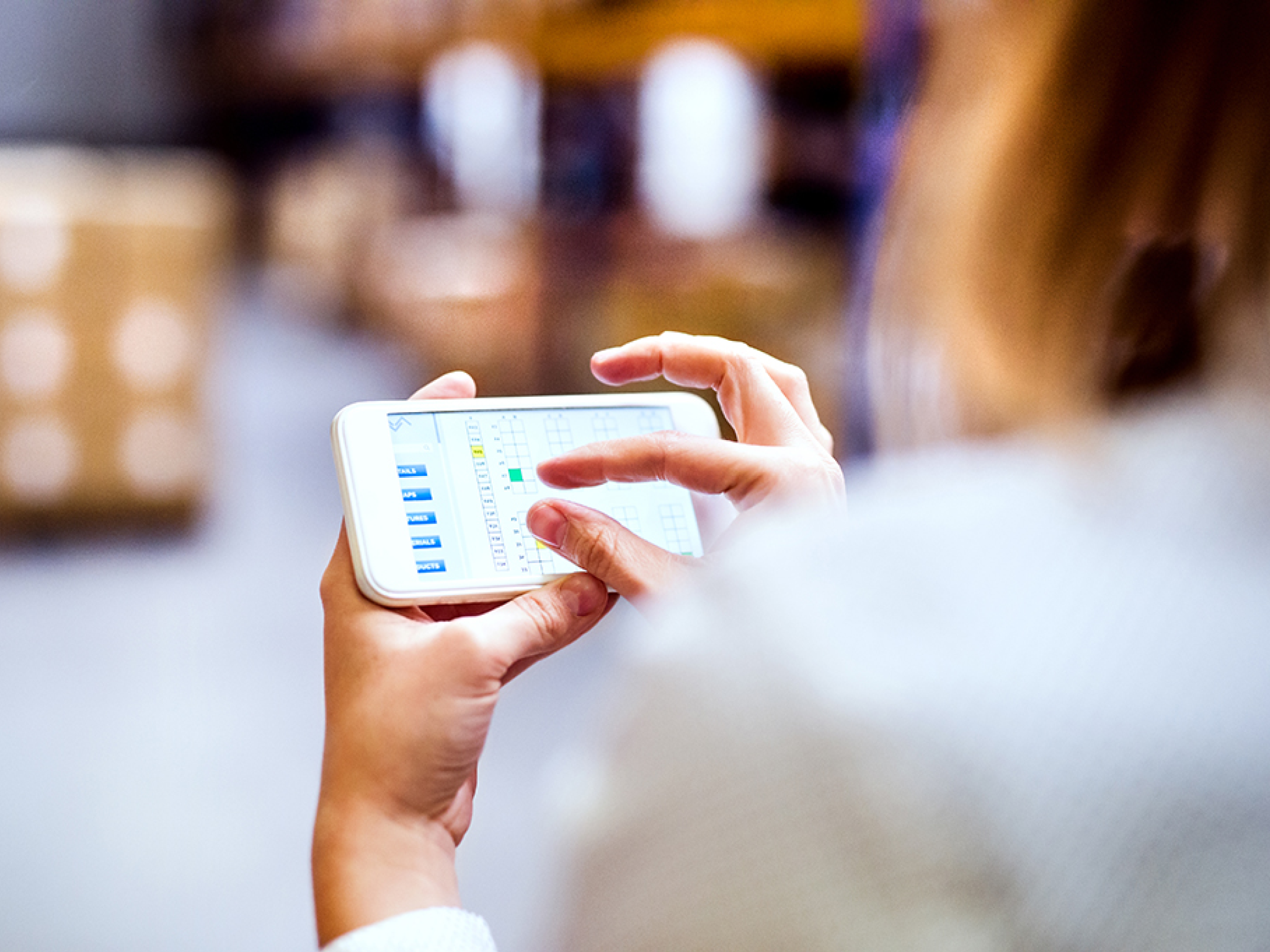 Unrecognizable woman warehouse worker with smartphone  Blurred background 