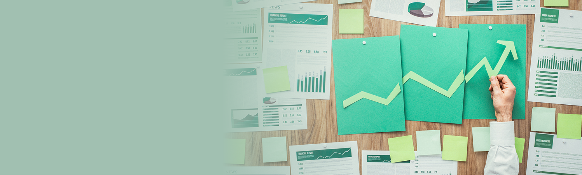 Businessman composing a successful financial chart with arrow going up, he is using green paper cuts, eco business and financial success concept