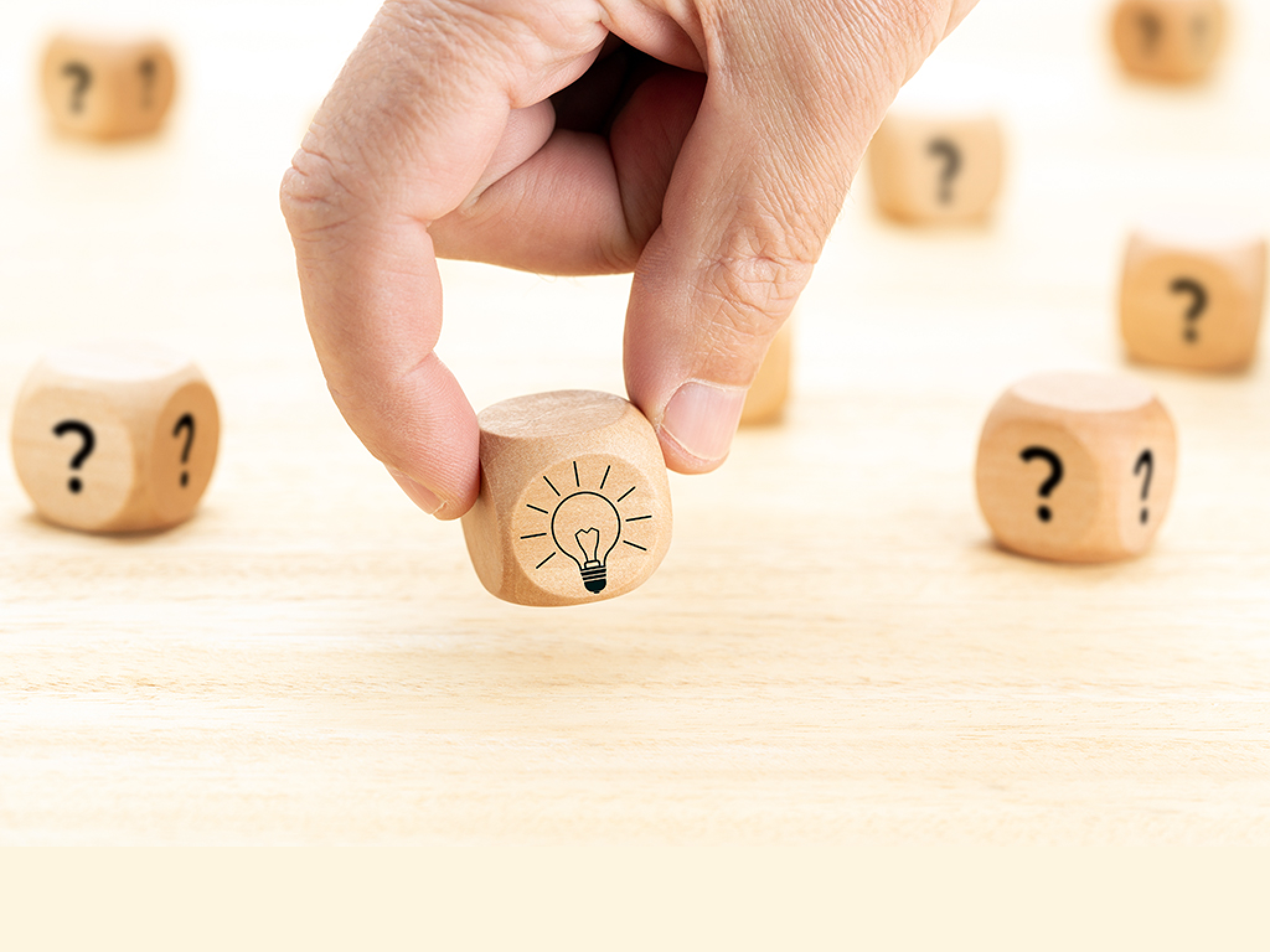 Creative idea or innovation concept  Hand picked wooden cube block with question mark symbol and light bulb icon on wood table