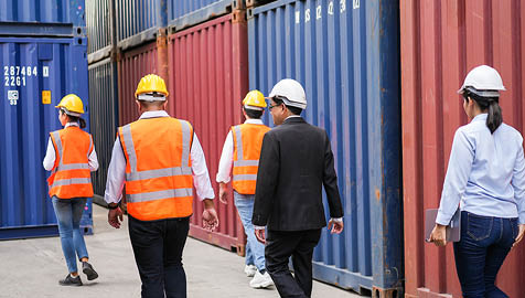 Back view group of warehouse worker discussing work with warehouse foreman. logistic business at dock. checking quality control at container site. shipping delivery process