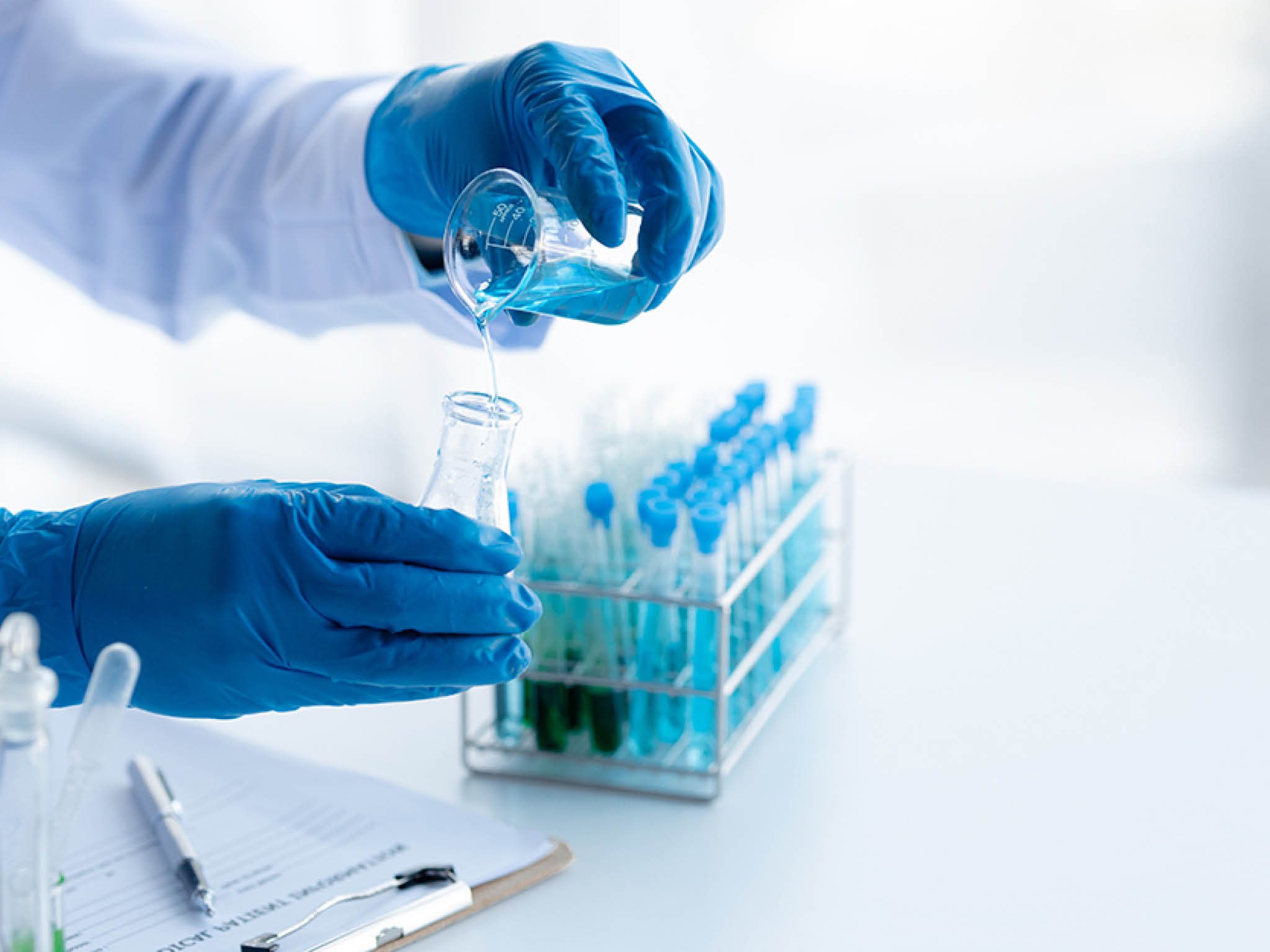 Lab assistant, a medical scientist, a chemistry researcher holds a glass tube through the blood sample, does a chemical experiment and examines a patient's blood sample. Medicine and research concept.