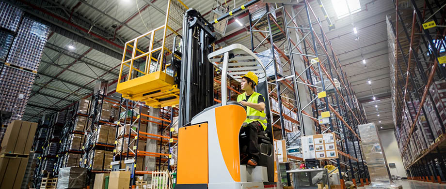 Forklift operator during work in large warehouse